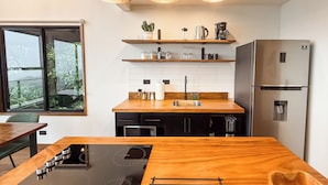 Una cocina moderna con encimera de madera, electrodomésticos de acero inoxidable e iluminación colgante.