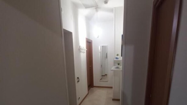 A narrow hallway with a door at the end, a light fixture on the ceiling, and a tiled floor. - Le Gemme Appartamenti  (Napoli)