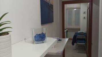 A hallway with a white counter, a potted plant, and a blue abstract painting on the wall.