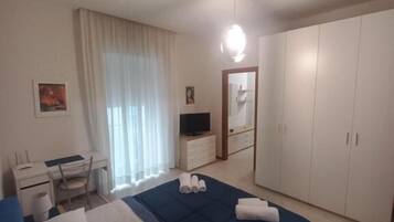 A bedroom with a bed, a desk, a chair, a television, and a wardrobe.