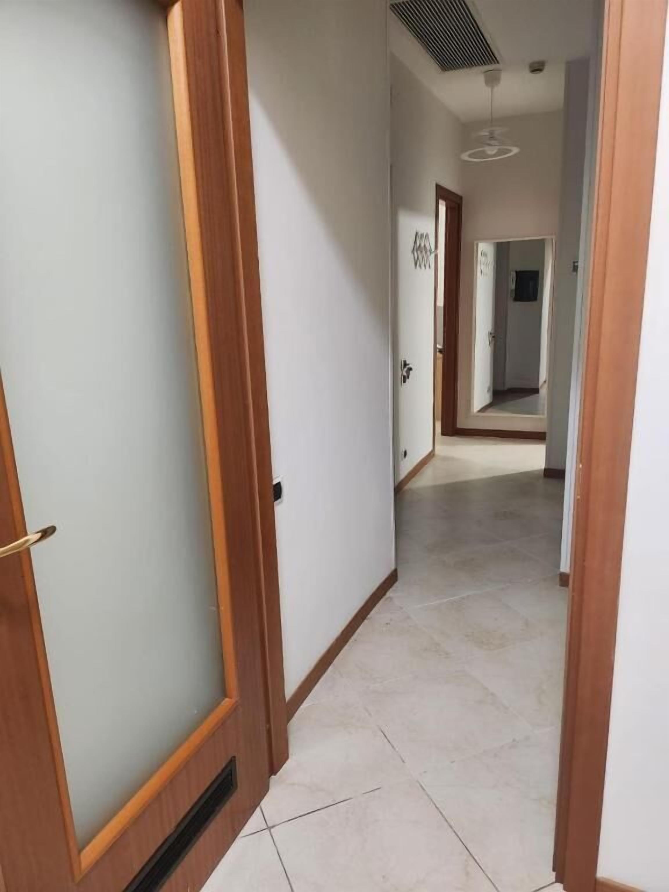 A hallway with wooden doors and a tiled floor.