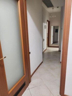 Un pasillo con puertas de madera y suelo de baldosas.
