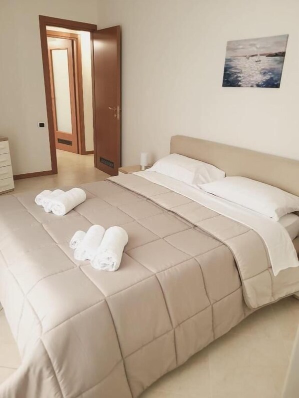 A hotel room with a bed, a door, and a wall-mounted picture.