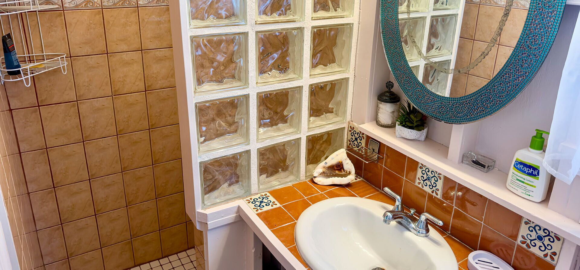 A bathroom with a white sink, a mirror, and a window with decorative glass panes.