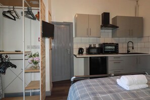 Ein gemütlicher Raum mit einem Bett, einer Küchenzeile mit Mikrowelle, einer Kaffeemaschine und Schränken.