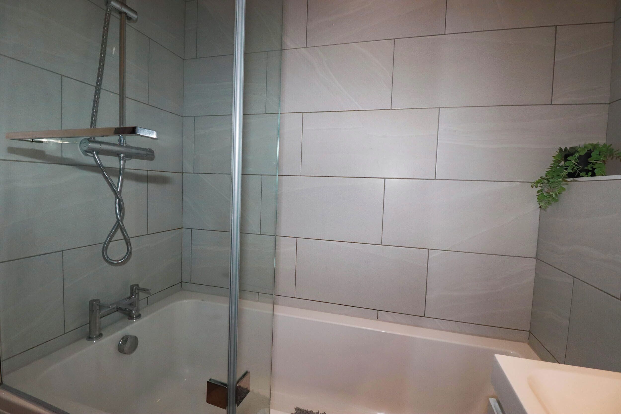 A modern bathroom with a glass-enclosed shower, a bathtub, and a sink.