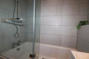 Ein modernes Badezimmer mit einer gläsernen Duschkabine, einer Badewanne und einem Waschbecken.
