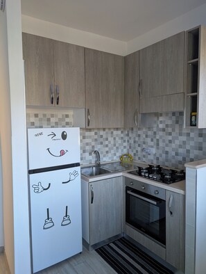 A compact kitchen with wooden cabinets, a stainless steel sink, and a gas stove. - Da Rose Marys Vacation Home in Policastro Bussentino. In the heart of Cilento (Campania)