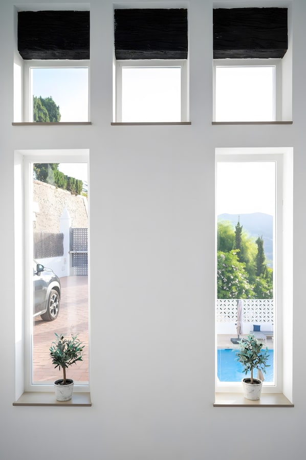 Una habitación con tres ventanas, cada una con vistas a diferentes paisajes.