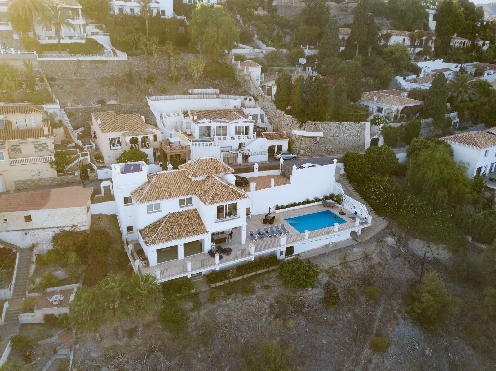 Una amplia villa con piscina, varios balcones y un jardín.