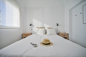 A bedroom with a large bed, two bedside tables, a window, and a hat on the bed. - Villa 'Romantica' with Sea View, Wi-Fi and Air Conditioning (Almuñécar)