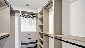 A walk-in closet with open shelving, a hanging rod, and a sliding door. - Salato (Pompano Beach)