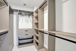 Ein begehbarer Kleiderschrank mit offenen Regalen, einer Kleiderstange und einer Schiebetür.