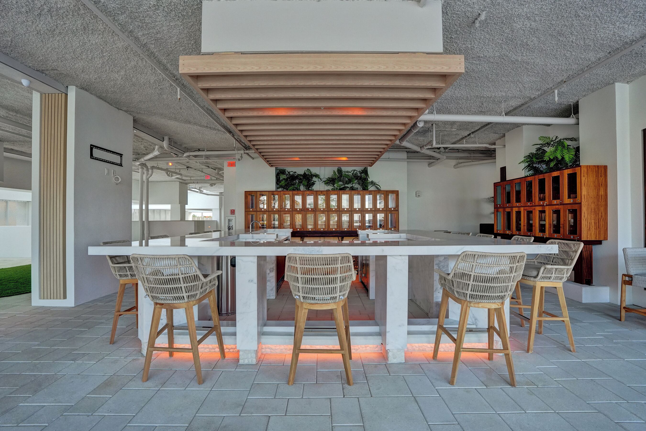A modern kitchen with a central island, bar stools, and wooden cabinets.