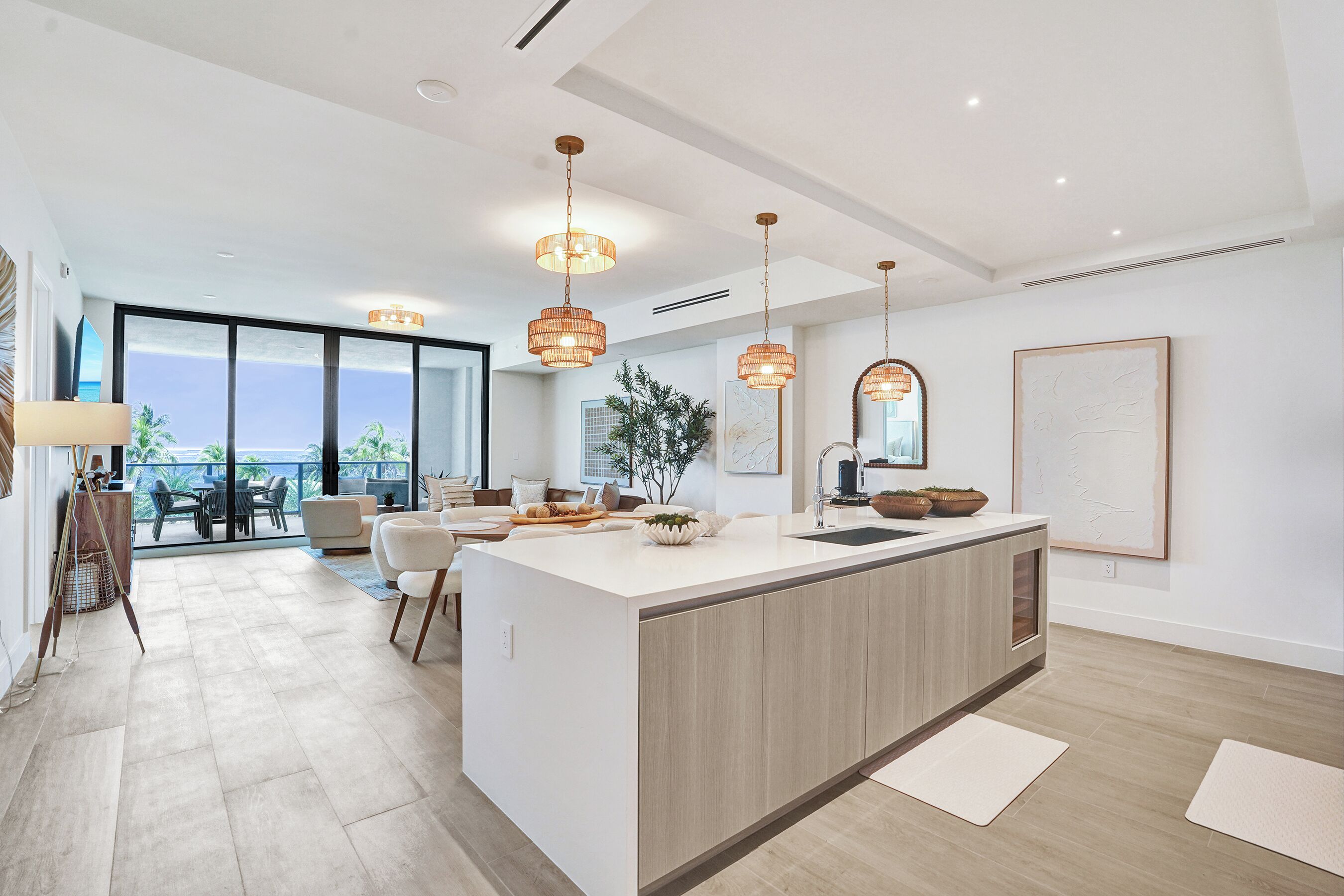 A modern kitchen with a central island, pendant lighting, and a view to the outside.