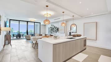 A modern kitchen with a central island, pendant lighting, and a view to the outside.