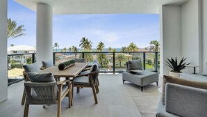 A modern balcony with a wooden table and chairs, a small round table, and a potted plant. - Salato (Pompano Beach)