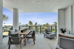 Ein moderner Balkon mit Holztisch und -stühlen, einem kleinen runden Tisch und einem Blumentopf.