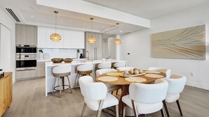 A modern kitchen with a central island, white cabinetry, and pendant lighting. - Salato (Pompano Beach)