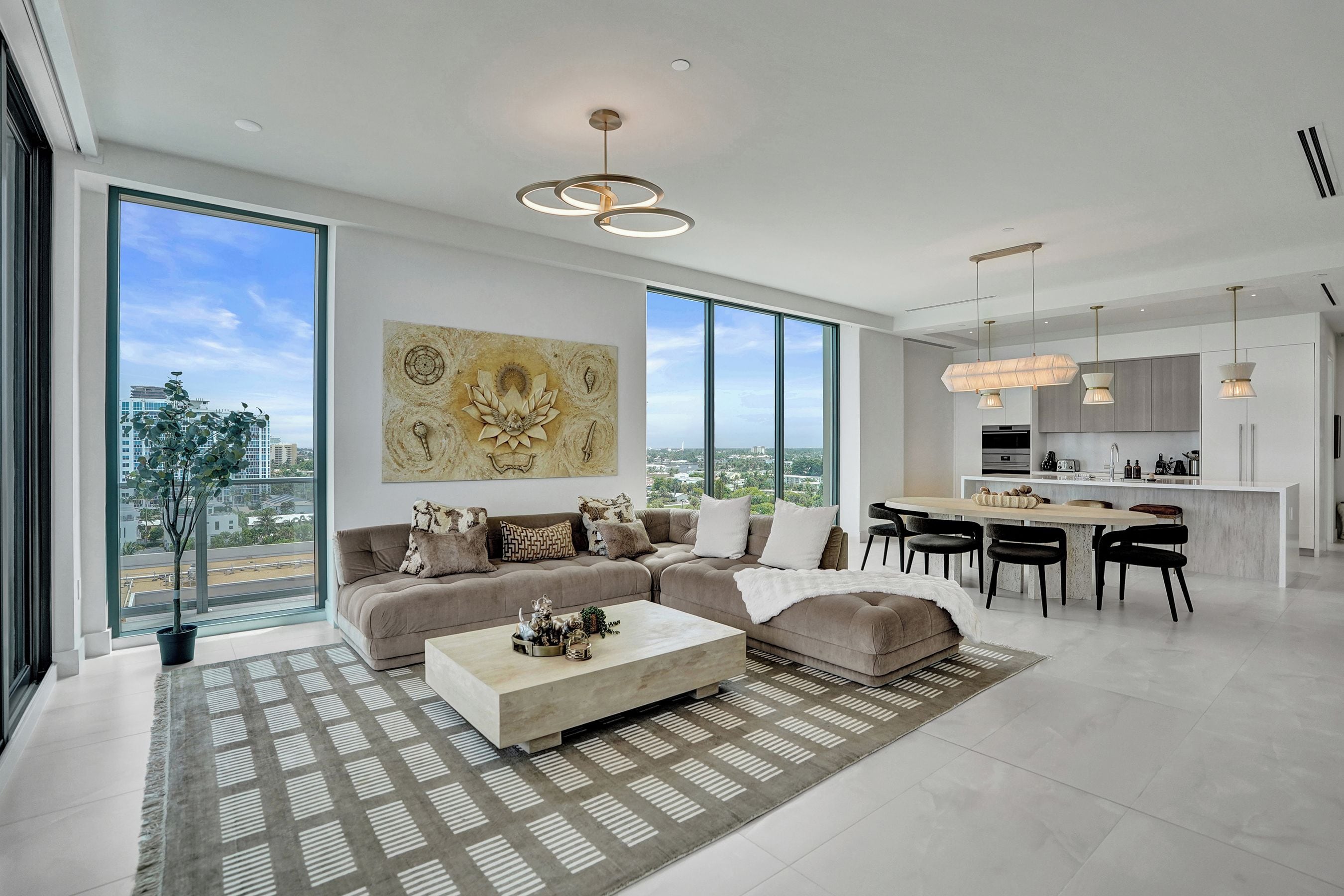 A modern living room with a large window, a sofa, a coffee table, and a view of the city.