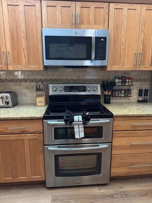 A kitchen with wooden cabinets, a stainless steel microwave, a stove, and a toaster. - The Canal House on Lake Harris (Tavares)