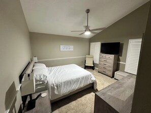 A bedroom with a bed, a dresser, a television, and a ceiling fan. - The Canal House on Lake Harris (Tavares)