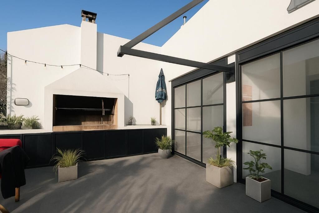 A modern outdoor kitchen area with a built-in oven, potted plants, and a large sliding glass door.