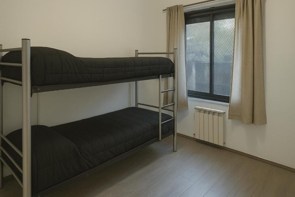 A bunk bed room with a window and radiator.