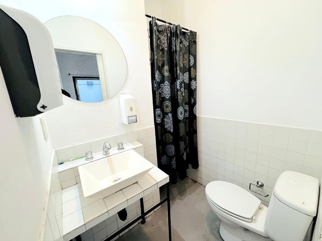 A bathroom with a white sink, a toilet, and a shower curtain with a floral pattern.
