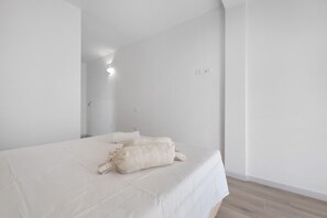 Ein schlicht eingerichtetes Hotelzimmer mit einem großen Bett, einem Nachttisch und einer Wandleuchte.