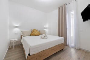 Ein Schlafzimmer mit einem Bett, einem Nachttisch, einem Fernseher und einem Fenster mit Vorhängen.