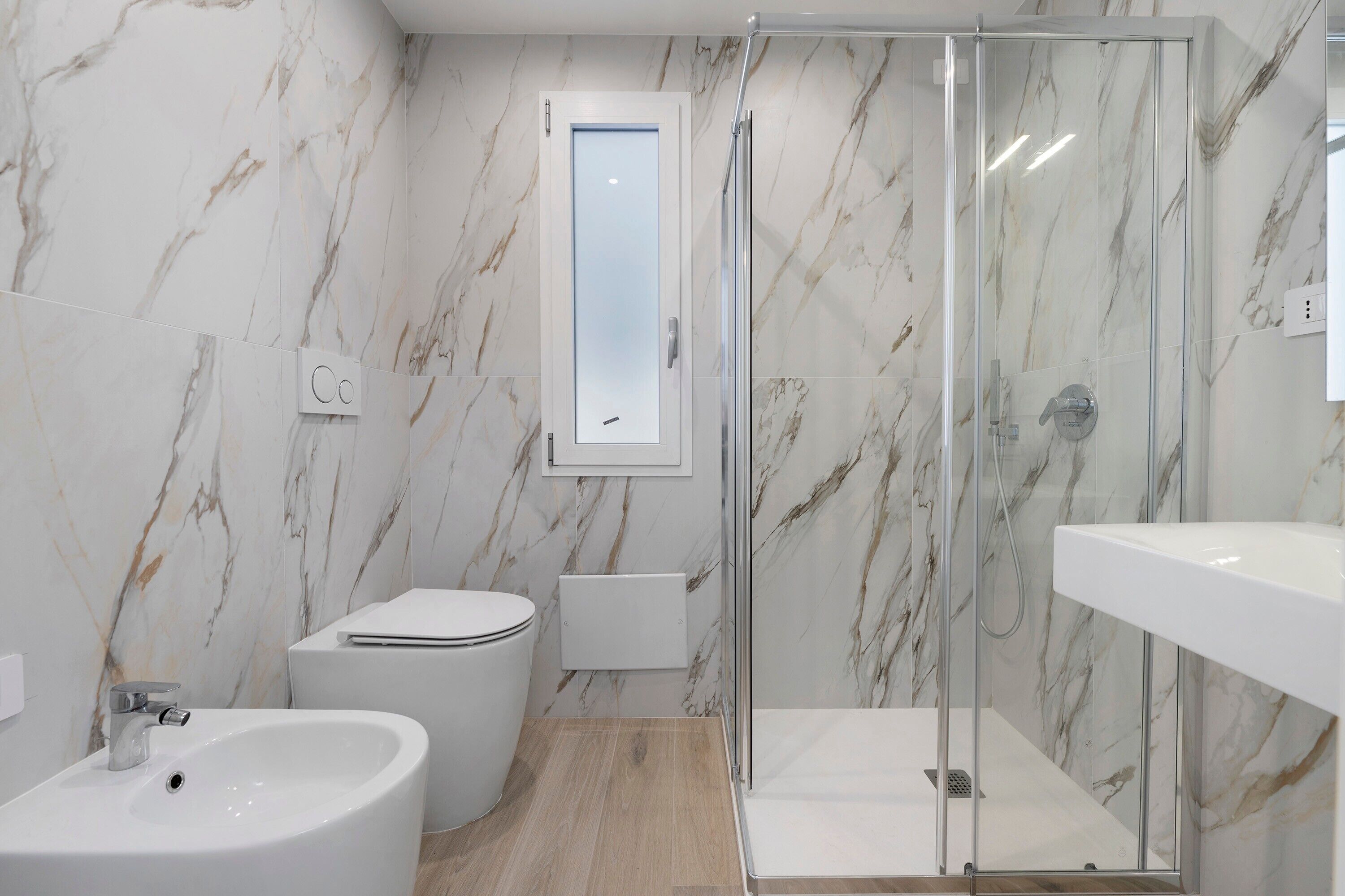 Une salle de bain moderne avec une douche à parois de verre, des toilettes et un lavabo.
