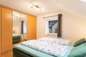 A bedroom with a bed, a wardrobe, a window, and a radiator.