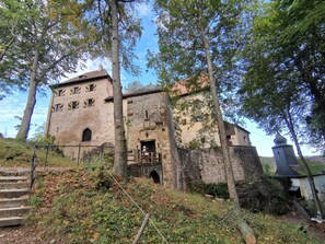 A historic stone building with a staircase leading up to a wooden door, surrounded by trees and vegetation. - Apartment 'Malbrich' with Private Terrace and Wi-Fi (Gräfenberg)