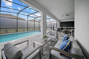A covered outdoor area with a pool, seating, and a barbecue station. - 8BR house at Windsor Cay Resort (Clermont)