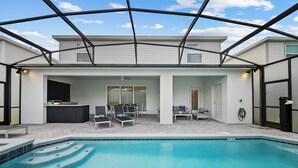 Ein Poolbereich mit überdachter Terrasse, Liegestühlen und einer Bar.