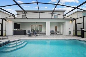 Ein Poolbereich mit überdachter Terrasse, Liegestühlen und einer Bar.