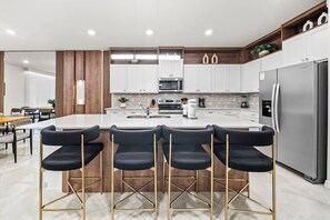 Een moderne keuken met een centraal eiland, barkrukken, roestvrijstalen apparatuur en houten details.