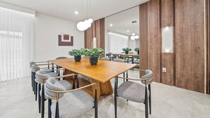 Ein moderner Konferenzraum mit Holztisch, grau gepolsterten Stühlen und Blumentöpfen.