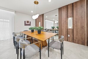 Ein moderner Konferenzraum mit Holztisch, grau gepolsterten Stühlen und Blumentöpfen.