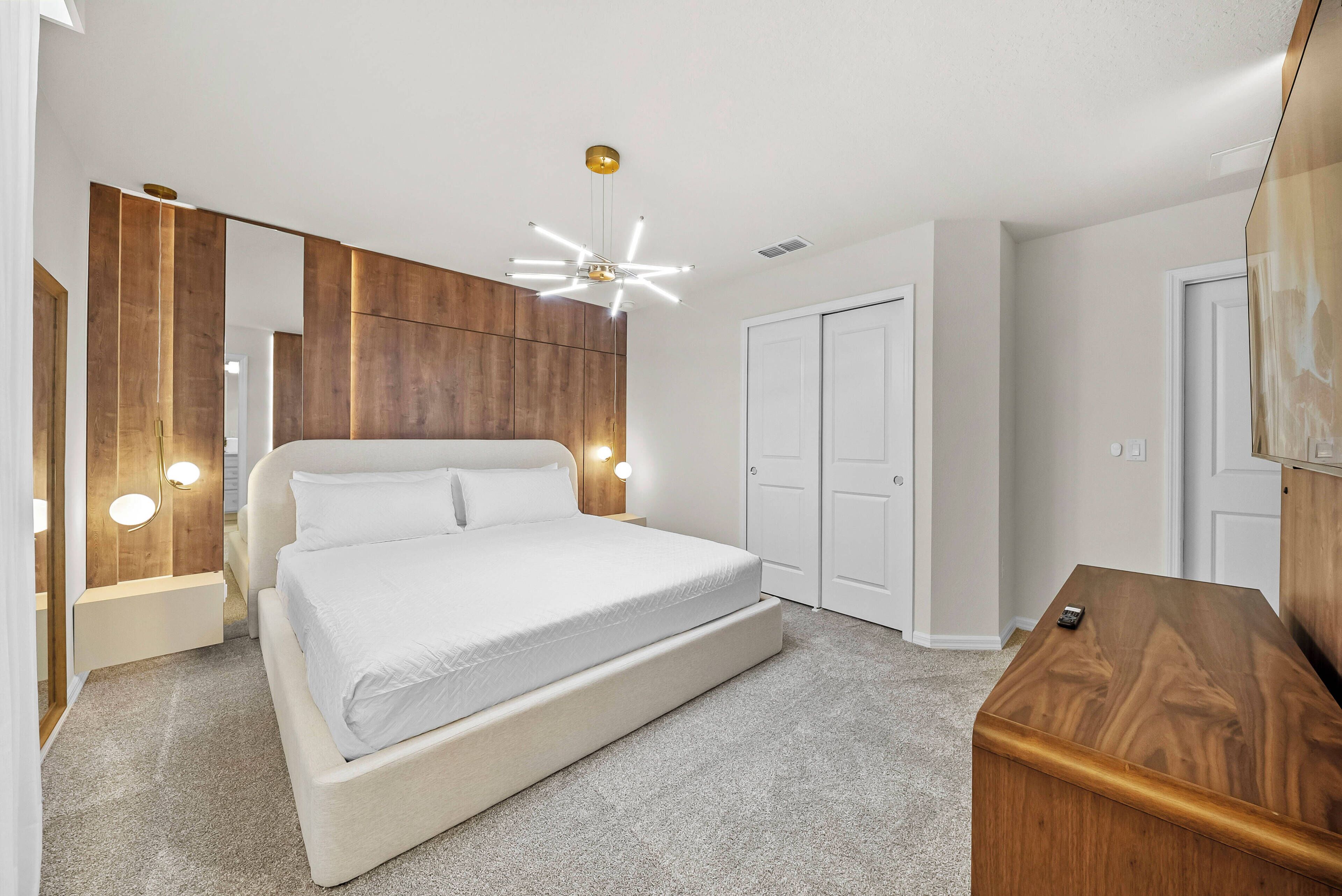 Quarto com cama, cabeceira de madeira, mesa de cabeceira, escrivaninha e guarda-roupa.