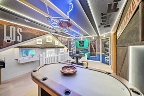 A pool table with a neon sign overhead, a 3D gaming console, and a wall with a car-themed mural. - 10BR house sleeps 27 near Disney (Clermont)