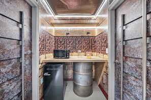 A compact kitchen with a microwave, a refrigerator, and a small table with a popcorn container. - 10BR house sleeps 27 near Disney (Clermont)