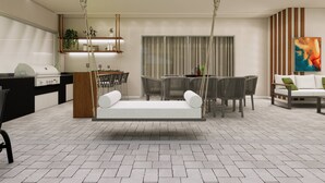 Un salon moderne avec une balançoire, un coin repas et une cuisine équipée d’un barbecue.
