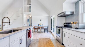 A modern kitchen with a central island, a built-in oven, and a stainless steel range hood.