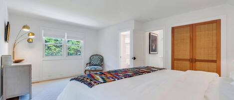 Une chambre à coucher avec un grand lit, une chaise, un bureau, une lampe et une armoire.