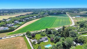 A residential area with houses, a large green field, a swimming pool, and a road.