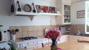Eine Küche mit Herd, Mikrowelle und Schränken. Auf dem Tisch steht eine Vase mit Blumen.