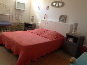 A bedroom with a bed, bedside tables, a wall-mounted TV, and a small shelf with books. - In La Croix Valmer, ground-floor villa unit with private pool for rent (La Croix-Valmer)