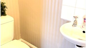 A bathroom with a toilet, a sink, and a shower area. - Ground Floor Studio - Willesden Green - Sleeps 4 (London)